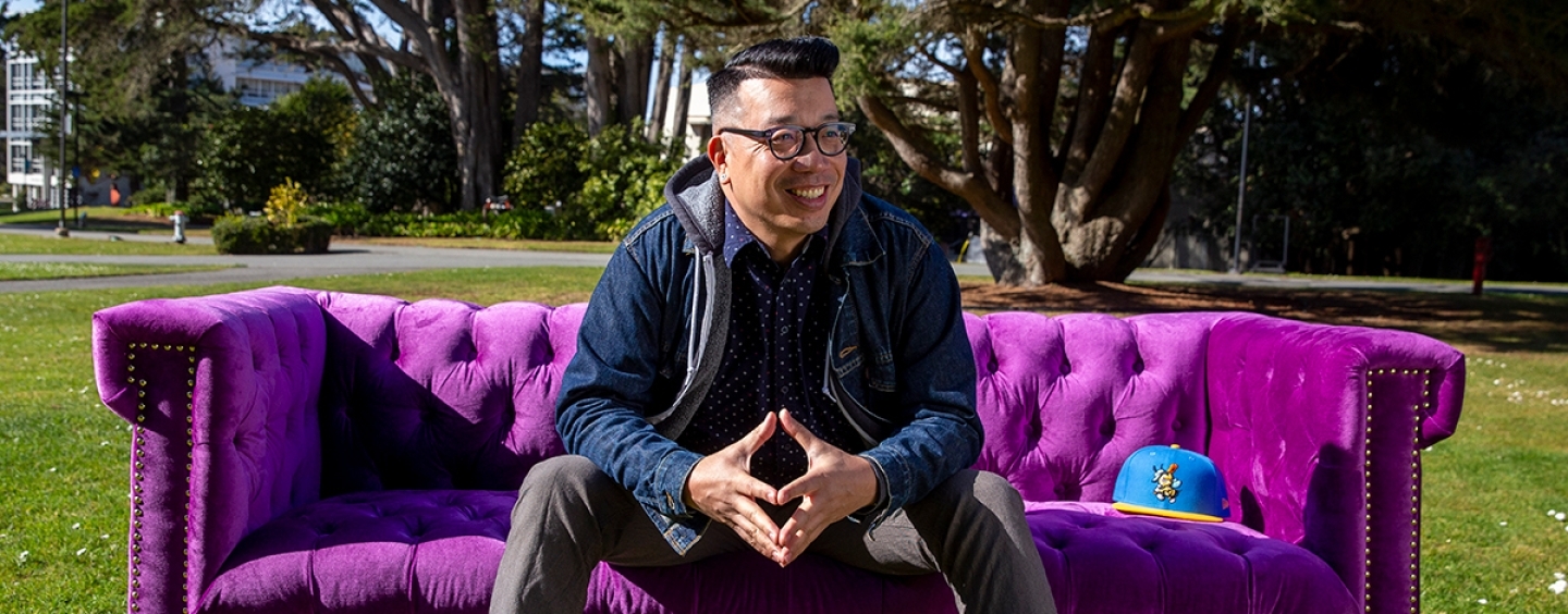 David Leroid sitting on a purple sofa on campus